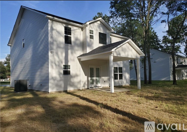 A white house with a garage is surrounded by trees.