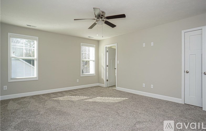 A room with a ceiling fan and carpeted floor.