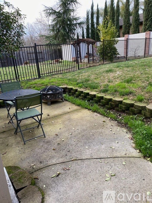 A backyard with a black fence and a green lawn chair.
