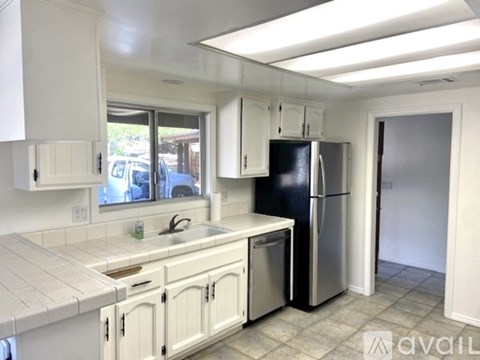A kitchen with white cabinets and a black refrigerator.