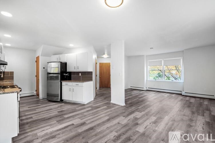 A spacious kitchen with white cabinets and a wooden floor.