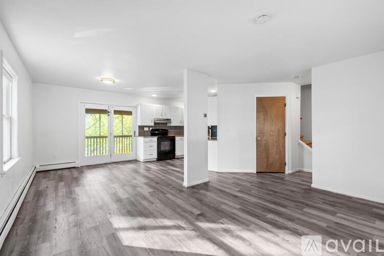 A spacious room with wooden flooring and white walls.
