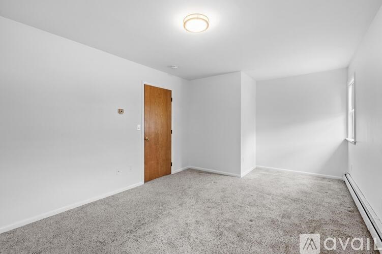 A room with a carpeted floor and a wooden door.