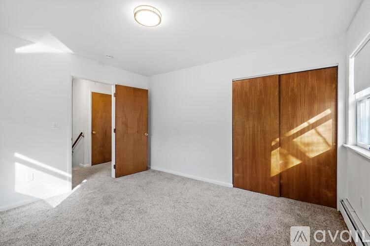 A room with a carpeted floor and two wooden doors.