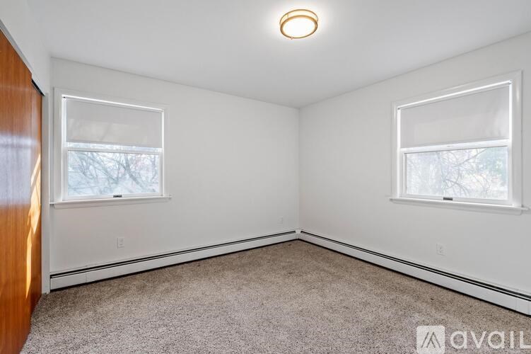 A room with a carpeted floor and two windows.