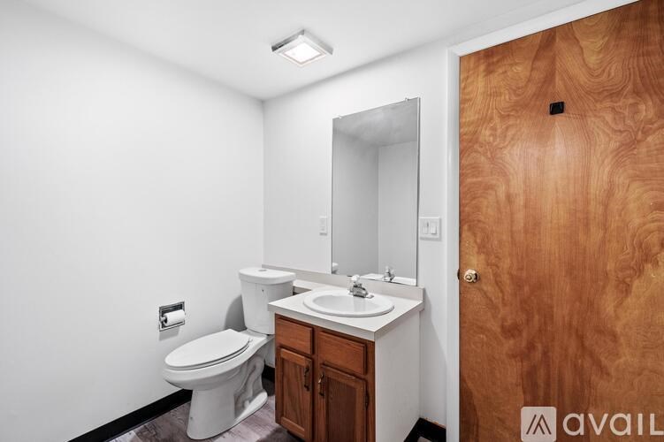 A bathroom with a toilet, sink, and mirror.