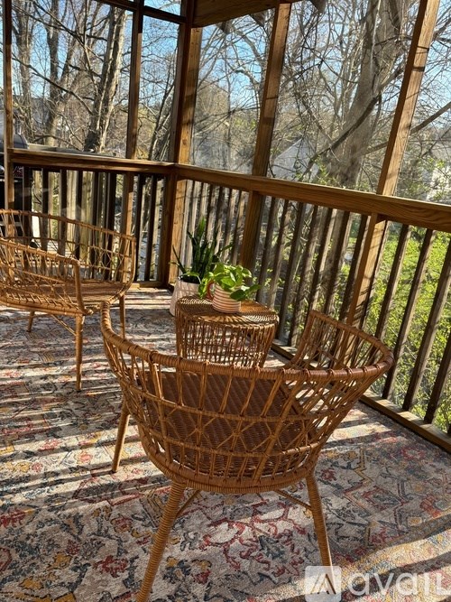 A sunny day on a screened porch with a wicker chair and table.