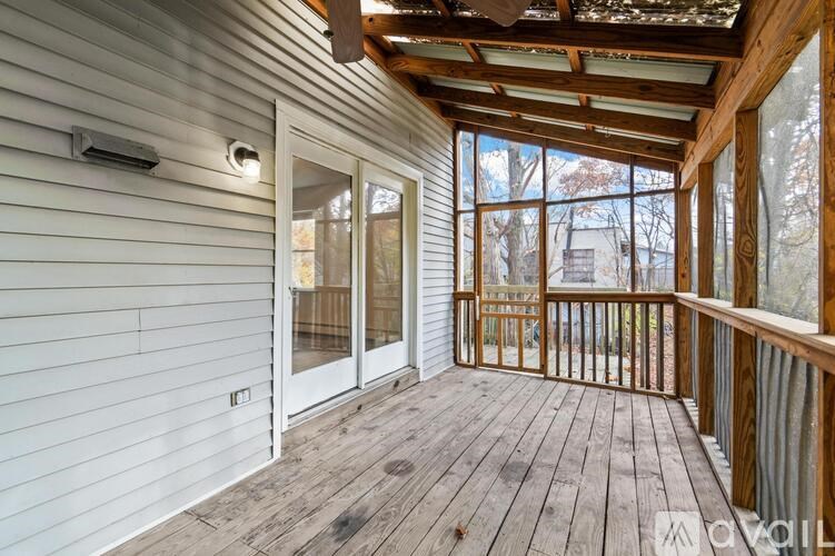 A sunroom with a wooden floor and ceiling, white walls, and a sliding glass door.