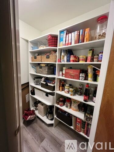A kitchen pantry with white shelves filled with food and drinks.