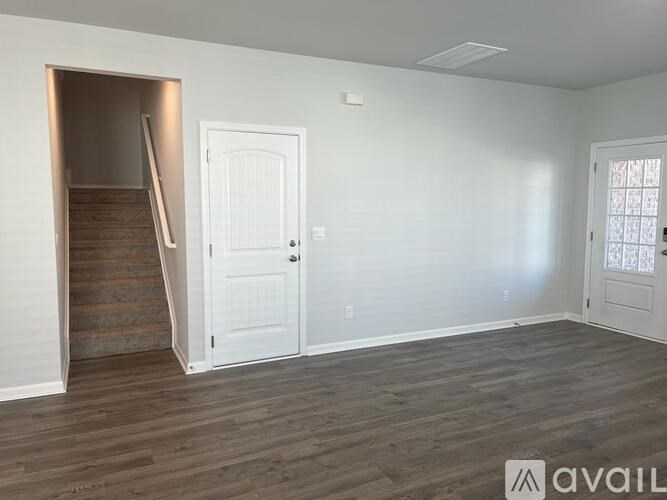 A room with wooden floors and a staircase leading to another room.