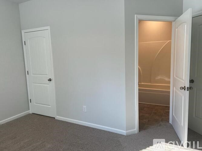 A white door is open to a room with a carpeted floor.
