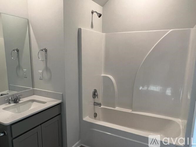 A white bathroom with a sink, mirror, and bathtub.