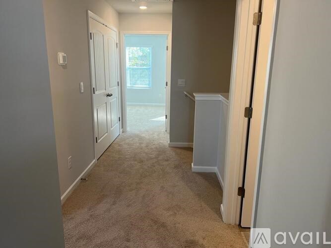 A hallway with a carpeted floor and white walls.