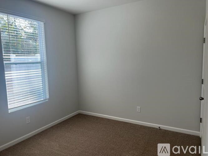 A room with a carpeted floor and a window with blinds.