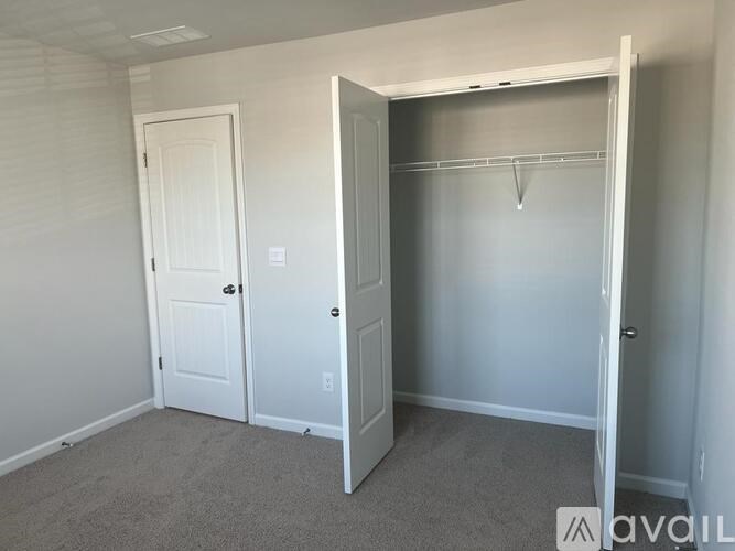 A bedroom with a white door and a white closet with a hanger.