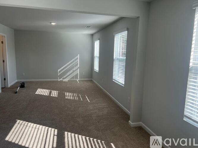 A room with carpeted floor and a staircase leading to another room.
