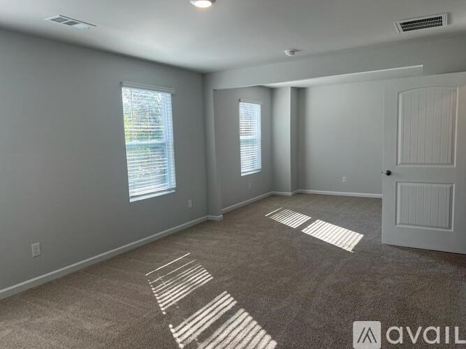 A room with a carpeted floor and a door is available for rent.