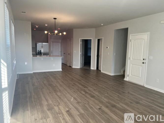 A spacious room with wooden flooring and a kitchen area in the background.