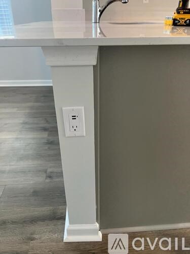 A white kitchen island with a sink and a power outlet on the side.
