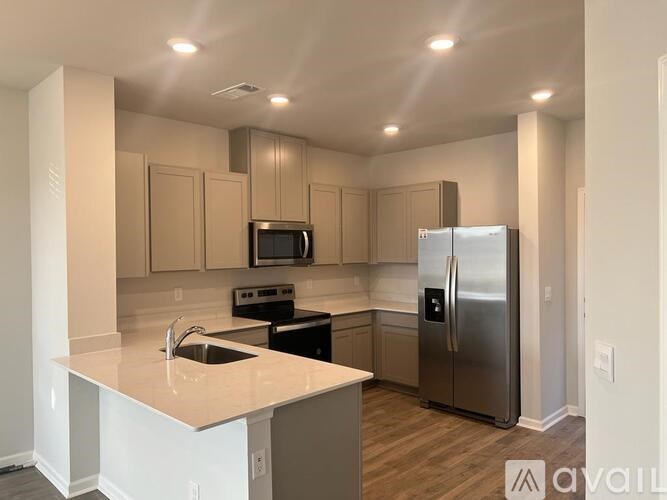 A kitchen with a refrigerator, microwave, oven, and sink.