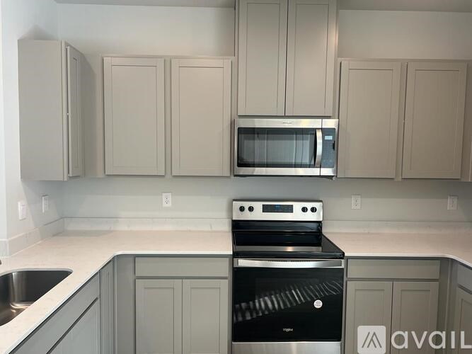 A kitchen with a black oven and grey cabinets.