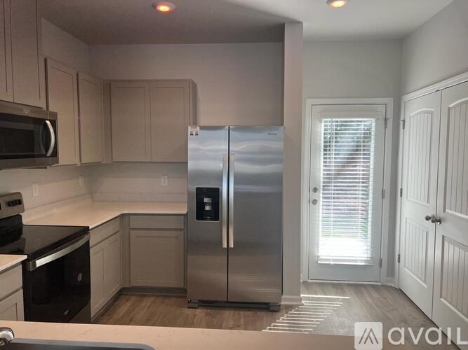 A kitchen with a stainless steel refrigerator and wooden cabinets.