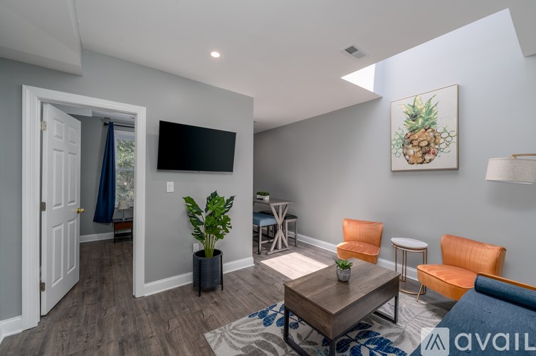 A living room with a television, a pineapple painting, and a plant.