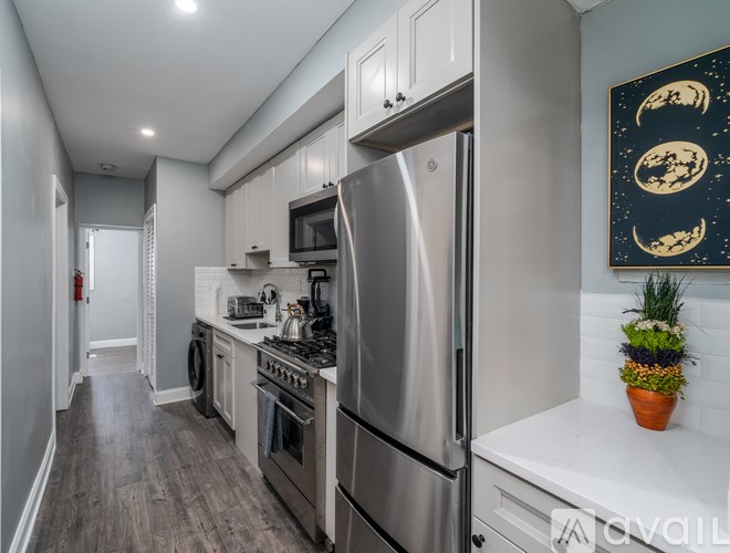 A modern kitchen with a stainless steel refrigerator and wooden flooring.
