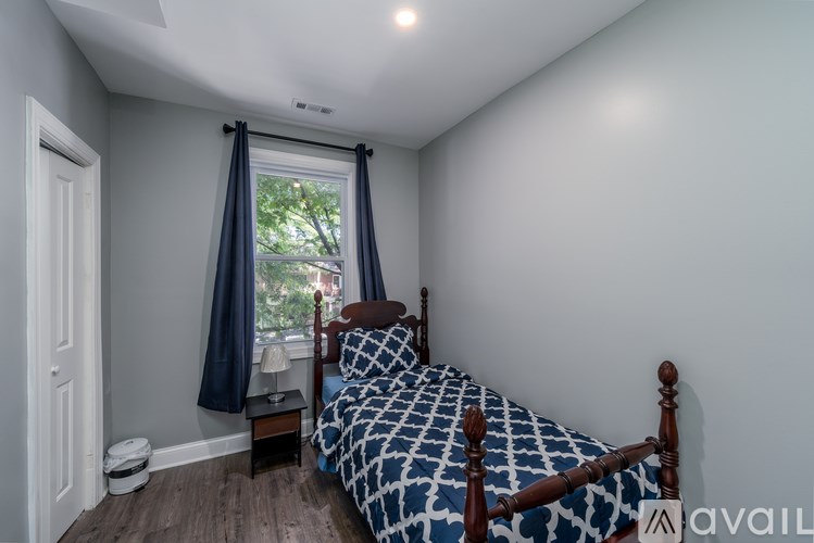 A bedroom with a bed, nightstand, and window with curtains.