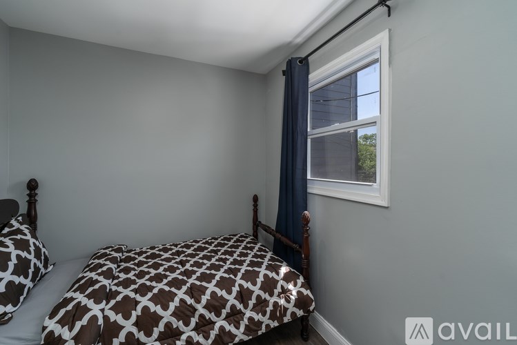 A bedroom with a bed and a window with a blue curtain.