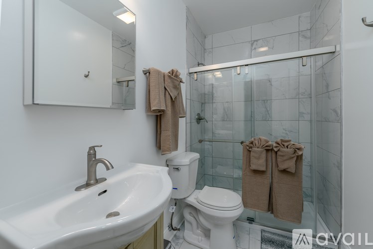 A bathroom with a white sink, toilet, and shower area.