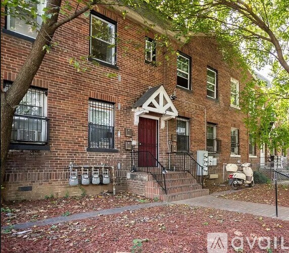 A brick building with a red door and a black railing.