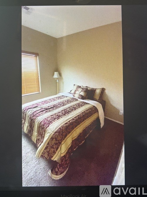 A bedroom with a bed, pillows, and a lamp.