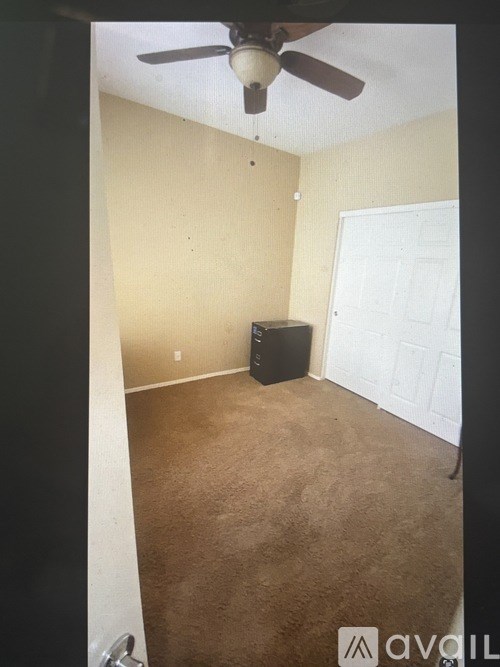 A room with a ceiling fan and a white door.