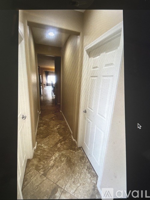 A hallway with a tiled floor and a white door.