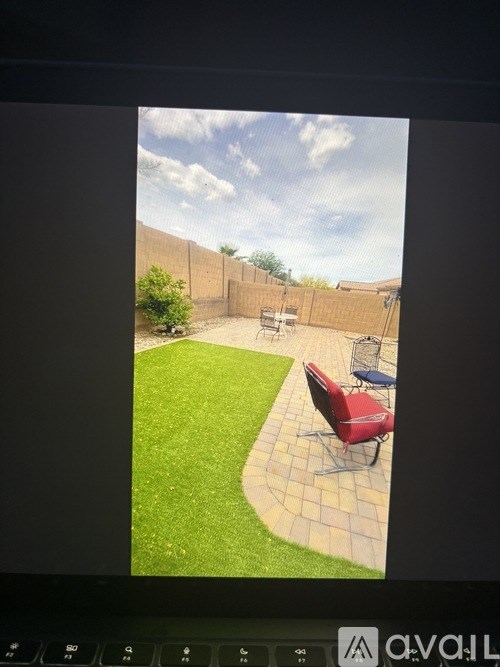 A backyard with a red chair and a green lawn.