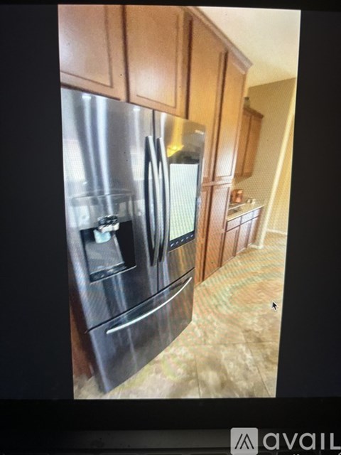 A stainless steel refrigerator with a black handle and a black drawer is in a kitchen.