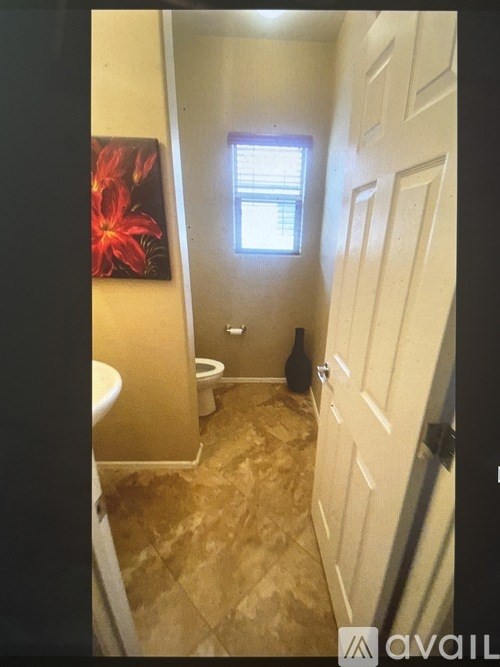 A bathroom with a toilet, sink, and a window.