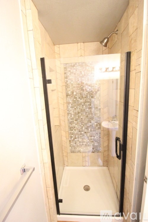 A shower with a glass door and a tiled wall.