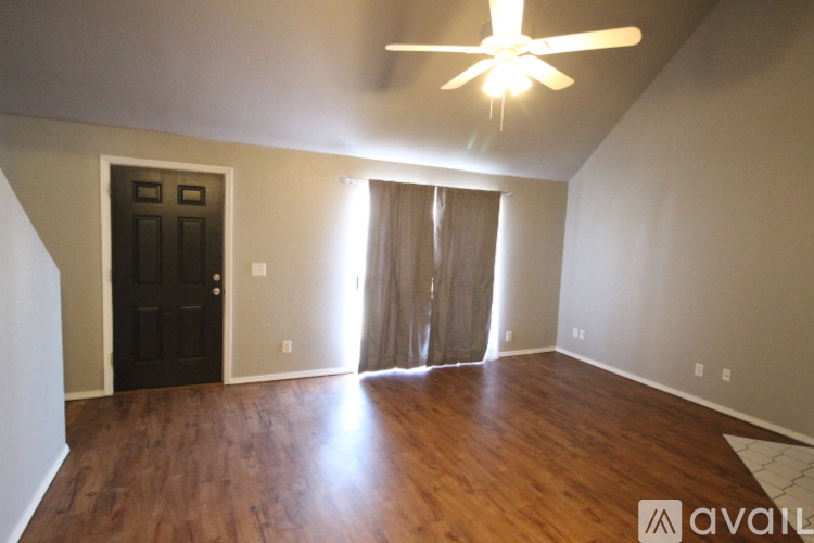 A room with a ceiling fan and wooden flooring.