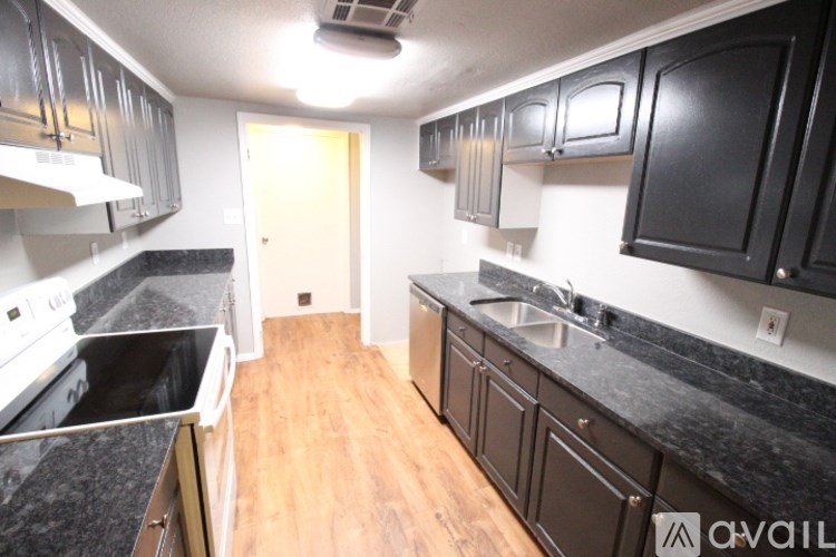 A kitchen with black cabinets and a white stove top oven.