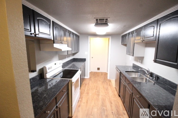A kitchen with black cabinets and a wooden floor.