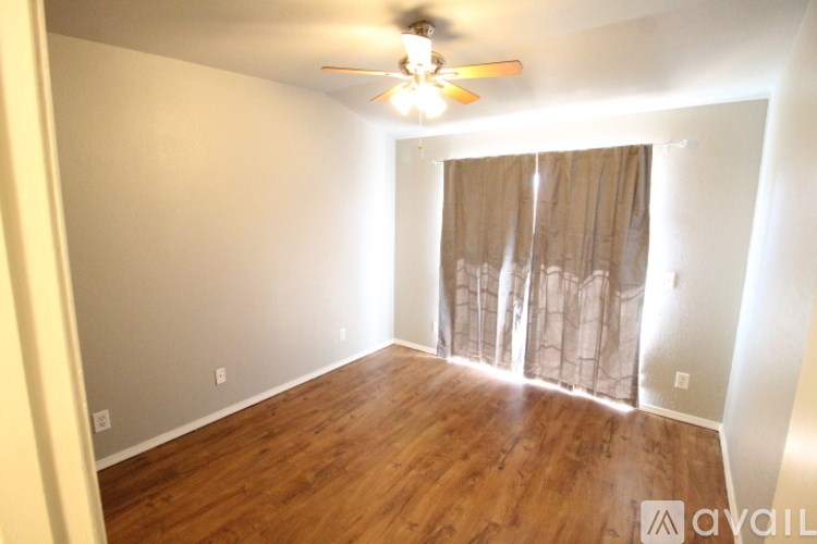 A room with a ceiling fan and wooden flooring.