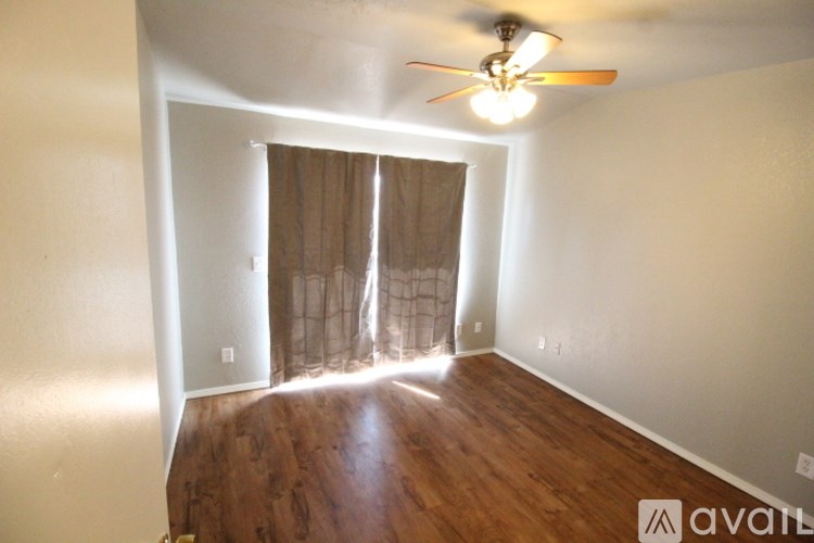 A room with a ceiling fan and wooden flooring.