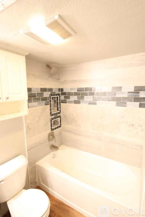 A white toilet sits next to a white bathtub in a bathroom.