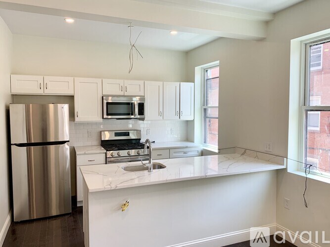A kitchen with a refrigerator, microwave, oven, and sink.