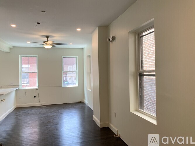 A room with a ceiling fan and two windows.