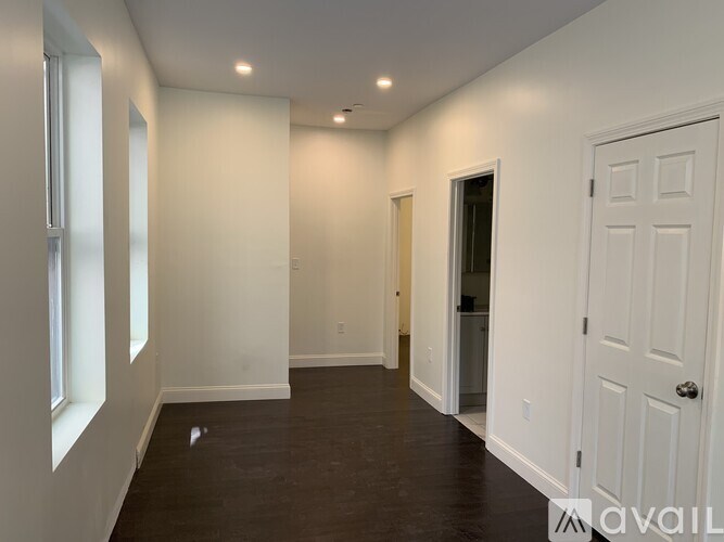 A spacious room with white walls and a wooden floor.