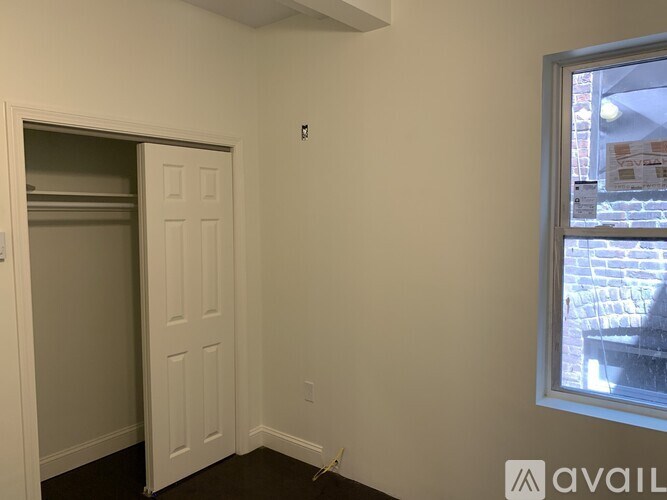 A room with a white door and a window showing a street view.