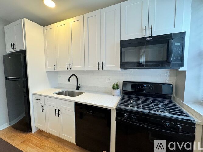 A kitchen with black appliances and white cabinets.